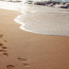 Footsteps on beach with waves